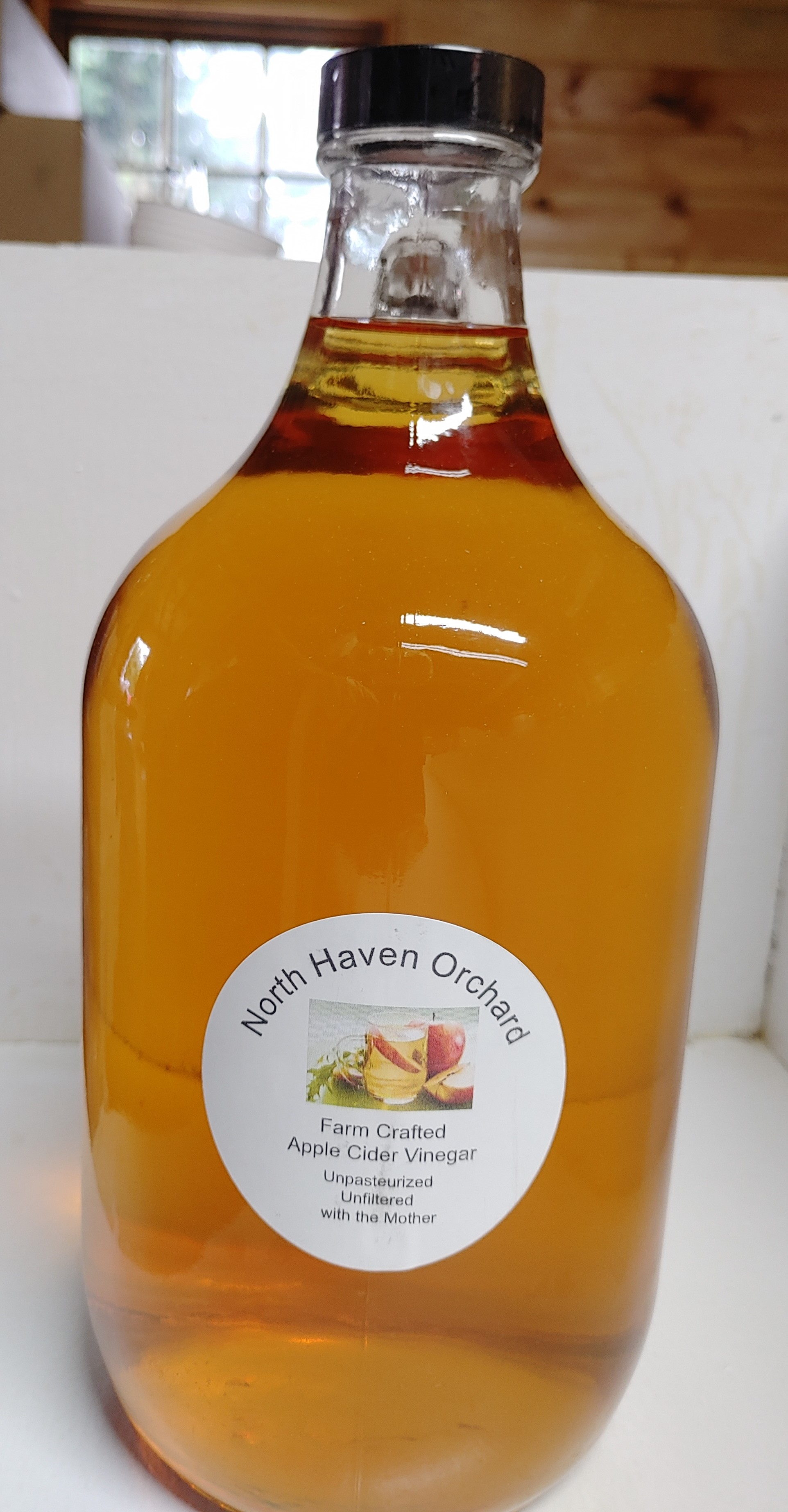 Bottle of North Haven apple cider vinegar displayed at a farmers market table.